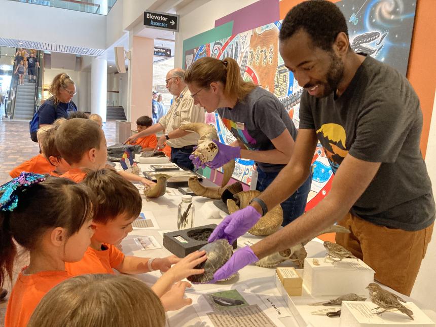 Cameron shows a group of children a turtle shell during an educational event at the Denver Museum.